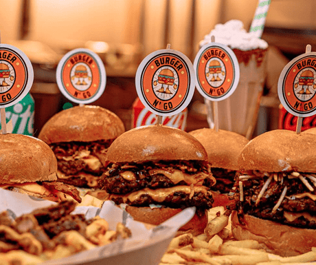 Beef burger with cheese and pickles served on a sheet of custom printed greaseproof paper with a custom burger flag stuck in the bun