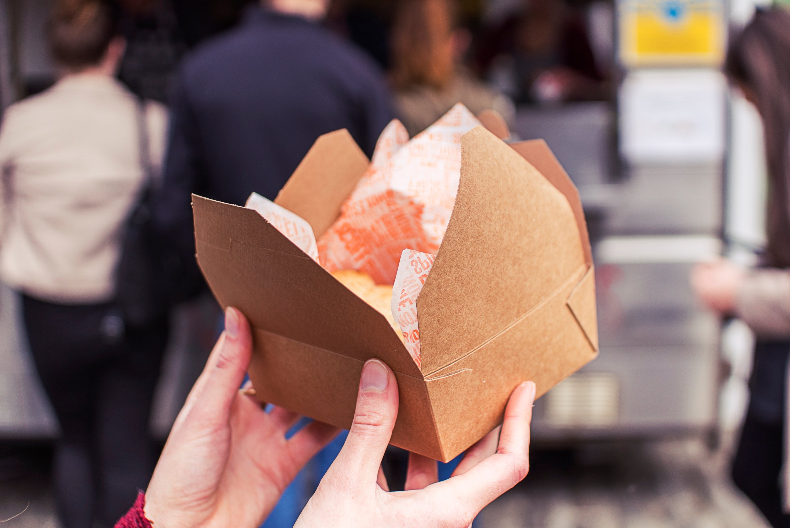 kraft box and greaseproof paper containing food being held at a street food festival