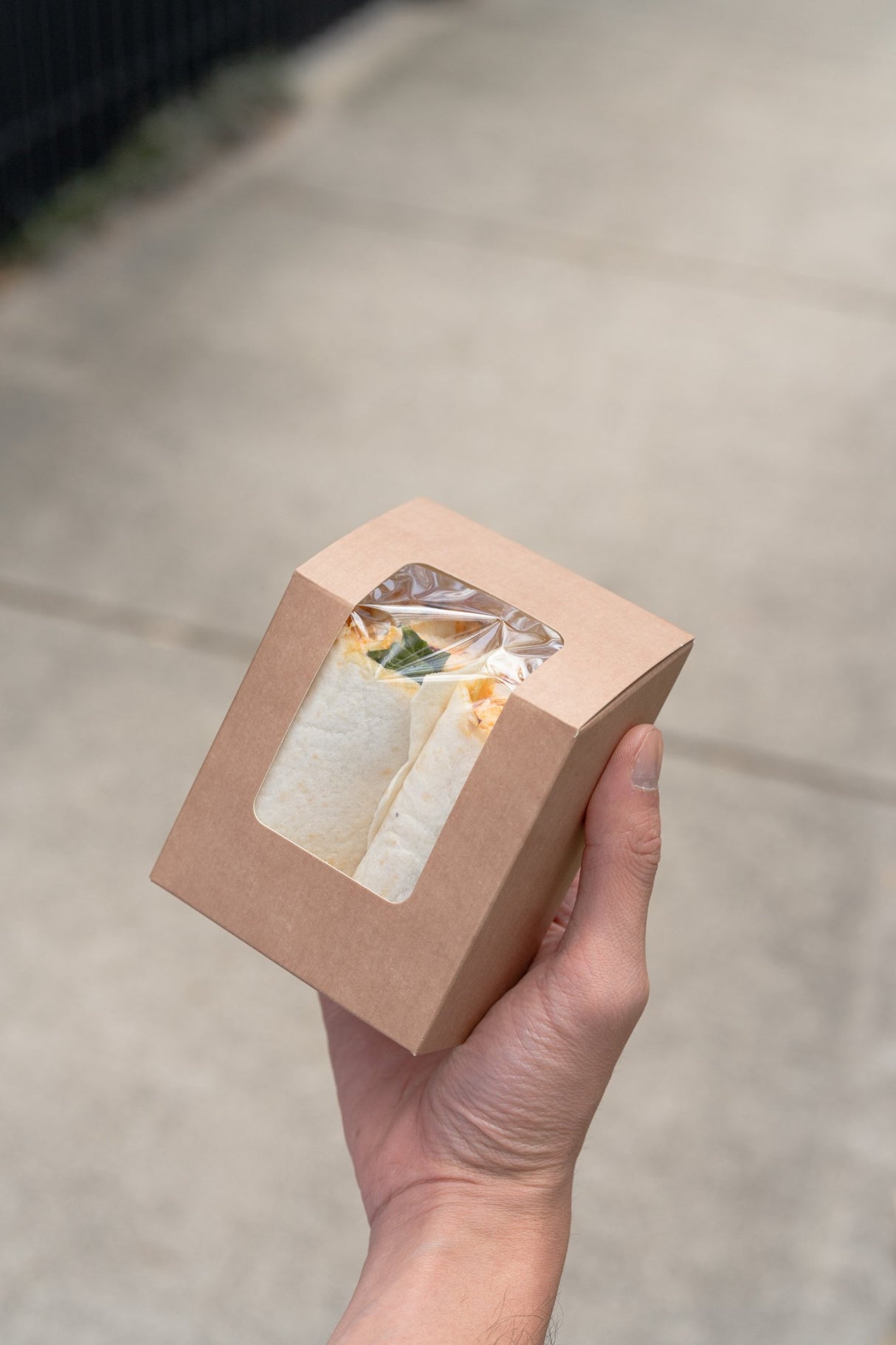 kraft wrap box containing a tortilla wrap with clear window in a mans hand