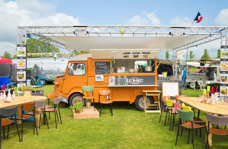 A orange food van serving takeaway food at a festival using sustainable packaging