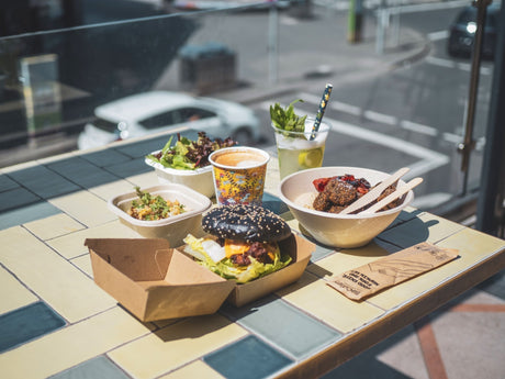 Compostable takeaway packaging on a table at a outdoor cafe serving burgers and coffee