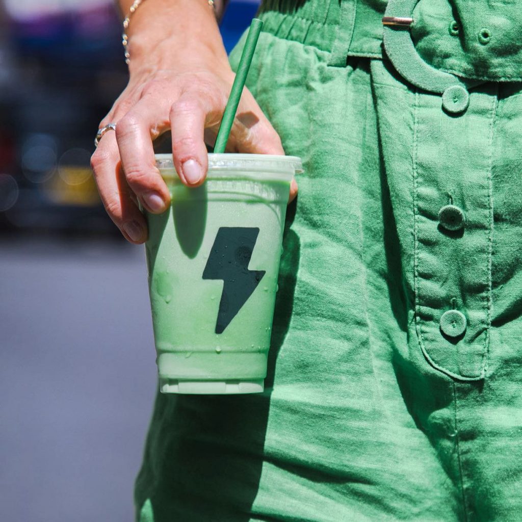 custom printed 16oz cold cup with a paper straw being held by a customer outside