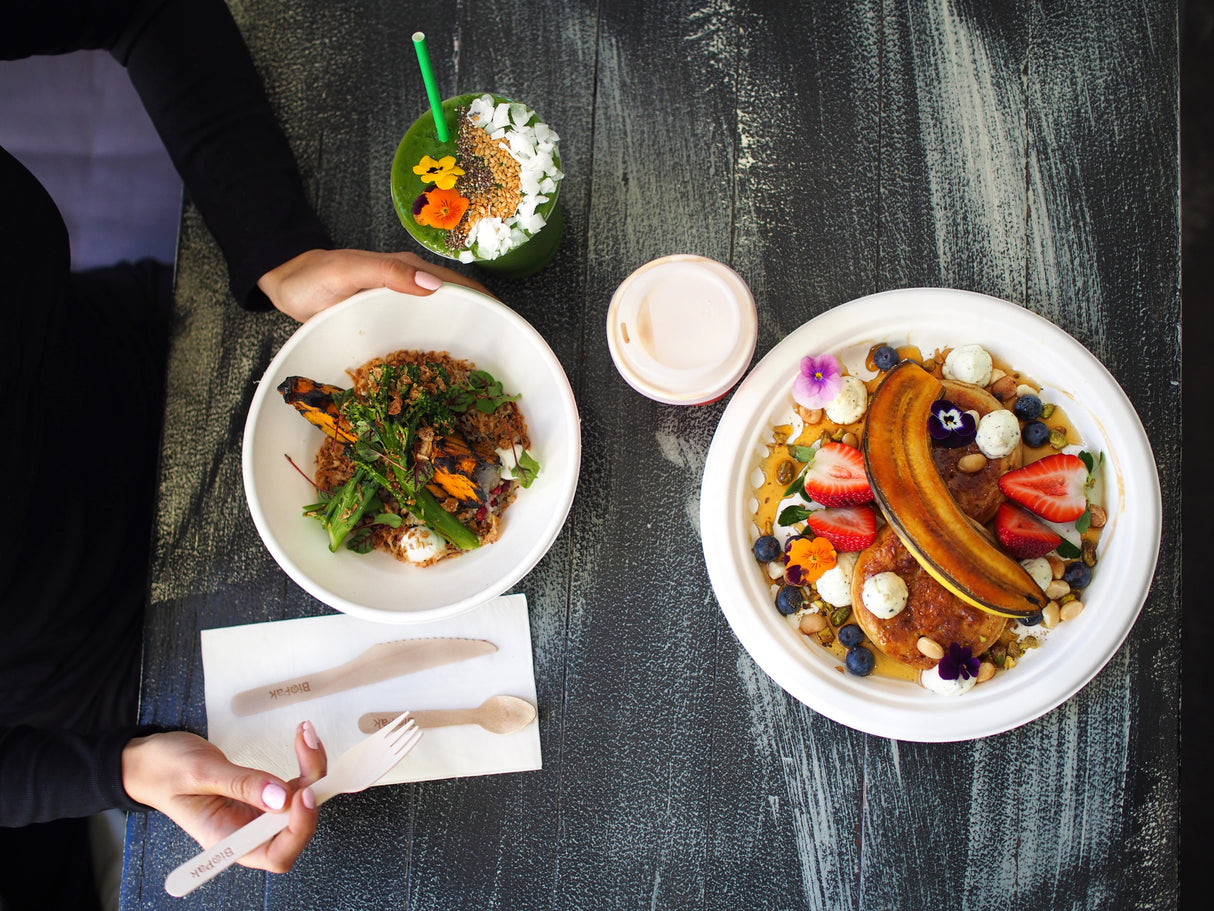 disposable bagasse plates with bagasse bowls and a cold takeaway drink cup