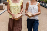 kraft boxes being used for takeaway food carried by two women walking in a park