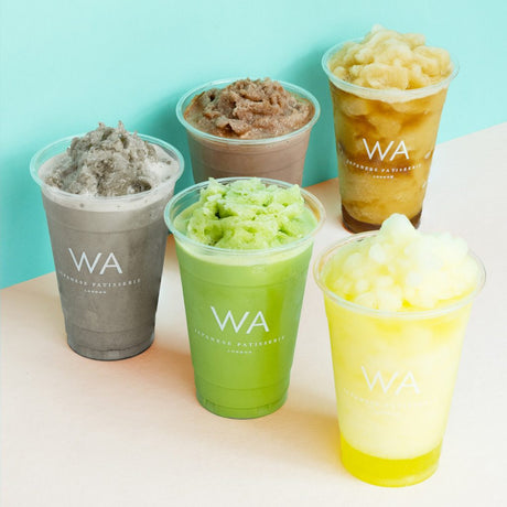 custom printed pet clear cold cups with wa cafe branding in white lined up on a counter top
